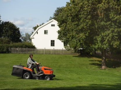 Husqvarna traktors veic pļaušanu lielā teritorijā